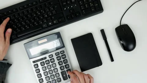 A man counts finances on a calculator and enters information into a computer Stock Footage 101839547