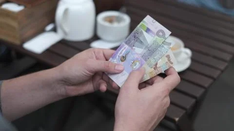 Man counts Kuwaiti dinars to pay for coffee in a street cafe Stock Photos