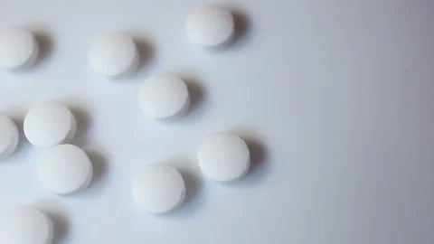 The man counts out small white round pills. On a white background, close-up, con Stock Footage 144643683
