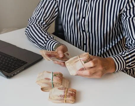 Man counts red paper 5000 rubles bills. Stock Photos