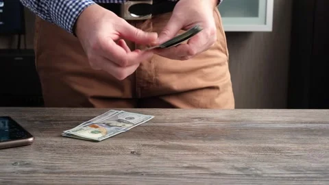 A man counts US $100 bills and lays them out on the table. Stock Footage 252067461