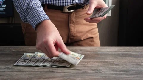 A man counts US $100 bills and lays them out on the table. Conceptual idea. Stock Footage 255700966