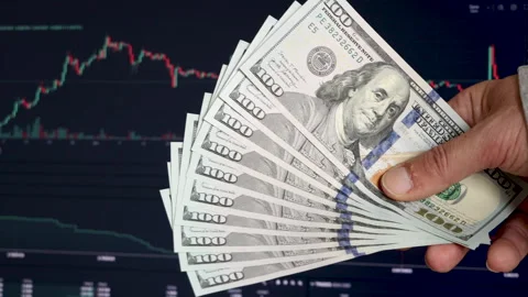 A man counts US dollars in front of a stock market price chart screen Stock Footage 303505048