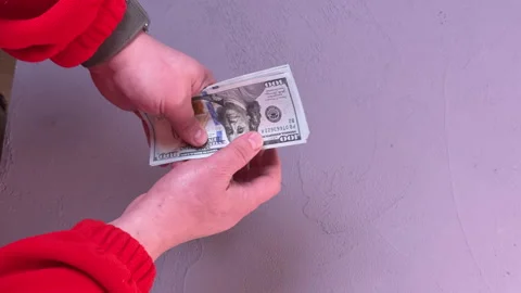 A man counts a wad of dollars over a table, top view, close-up on his hands Vidéo 304755884