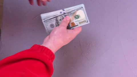 A man counts a wad of dollars over a table, top view, close-up on his hands Видео 304755885