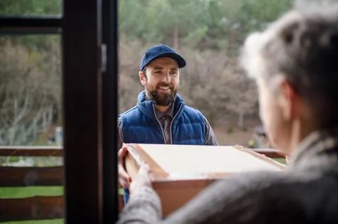 Man courier delivering parcel box to senior woman. Foto stock