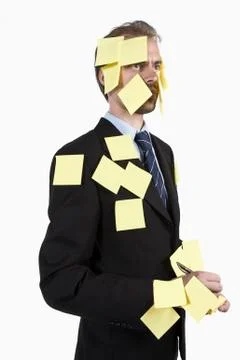 A man covered in blank adhesive notes and holding a pen Stock Photos