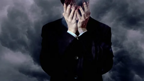 A man covered his face with his hands against a background of thunderclouds Stock Footage 236478803