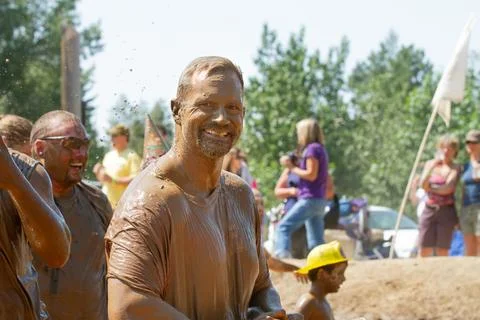 A man is covered in mud and is smiling Stock Photos