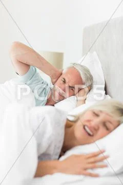 Man covering ears while woman shouting in bed Stock Photos