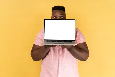 Man covering half of face with laptop with blank white screen and looking at Foto stock