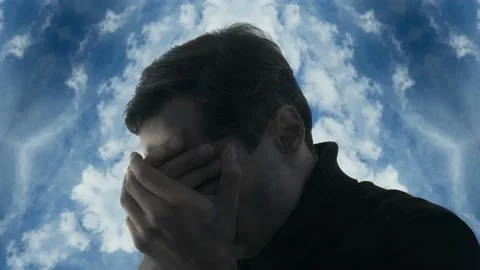 A man covers his face with his hands against the background of a kaleidoscope of Stock Footage 238536763