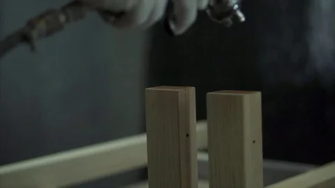 A man covers a tree with paint, paints a part with a spray. A factory worker  Stock Footage 84043313