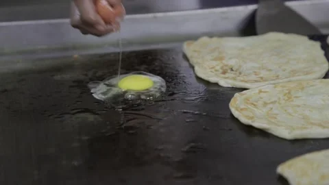 A man cracking eggs over a hot stove Stock Footage