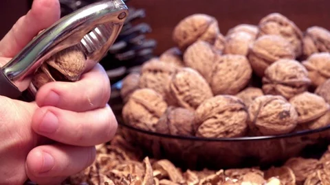 Man cracking nuts with metal nutcracker, close up. Video stock 87503777