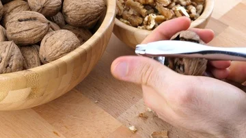 Man cracking walnuts with a nut cracker Stock Footage 85957941