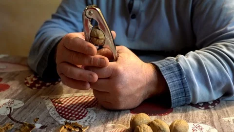 Man cracking whole walnuts with nut cracker at home, healthy eating and vitamins Stock Footage 123859423