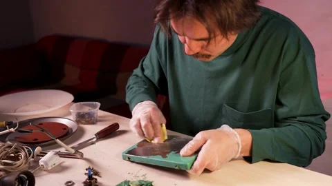 Man crafter disassembling vintage lamp, holding metallic base and sanding Stock Footage 323815733