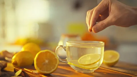As man crafts lemon tea his hands carefully add sliced citrus to mixture of Stock Footage 331315726