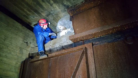 A man crawls out of an opening in an abandoned mine Stock Footage 129395085