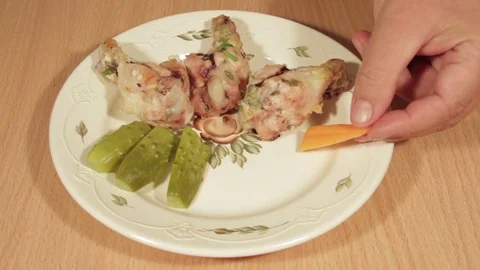 Man creates dishes portion from chicken wings with vegetables Stock Footage 71016624