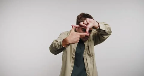 Man creates a frame with hands to show a perspective in a studio setting 動画素材 326788409
