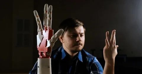 Man creates movement for mechanical plastic arm. Cybernetic robotic arm. Robots Stock Footage 85362277