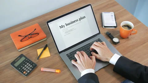 A man is creating a business plan writing on a laptop on a desk Vídeo Stock 155904092