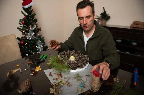 Man Creating Christmas Pinecone Decorations At Home In A Cozy Living Room Stock-Fotos