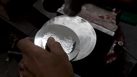 A man creating a hammering texture on a steel plate in workshop Stock Footage 244741399