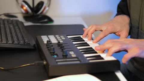 Man creating music on MIDI keyboard at desk Stock Footage 295877141