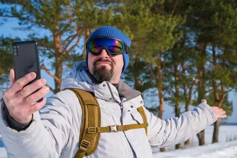 Man creating selfie video content for social media, wearing winter clothing.. Stock Photos