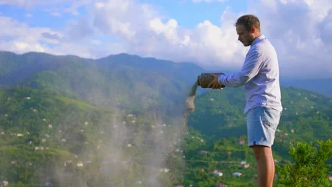 Man cremation urn scattering ashes in the mountains Stock Footage 246914448