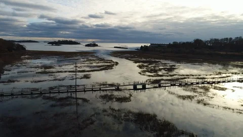 Man crosses bridge over marsh reflecting clouds Video stock 94008283