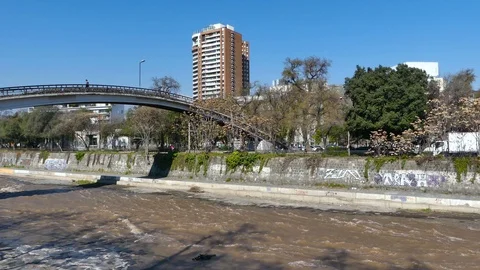 Man crosses bridge over the shallow, calm brown water Stock Footage 97100963