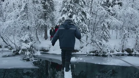 A man crosses a river in a winter forest over a wooden bridge and holds onto a 库存影片 156958003
