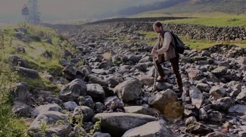 Man crosses a stream from right to left Stock Footage 41980629