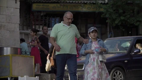 A man crosses the street while hanging his daughter in Bloudan, Syria Stock Footage 121807373