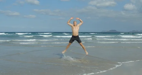 A Man Crossfit Training on a Beach doing Star Jumps/Jumping Jacks. Video stock 85511586
