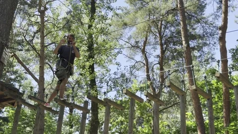 A man crossing an elevated rope obstacle course Stock Footage 312807992