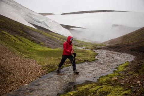 Man is crossing the small river in the geyser valley with snow Stock Photos