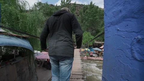 Man Crossing A Small Unstable Bridge Over A River Stock Footage 100451582