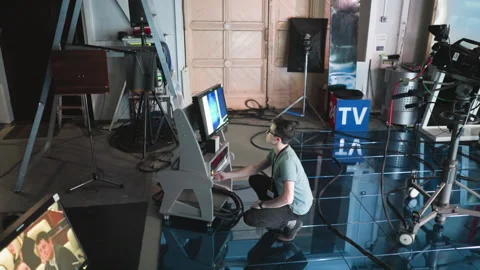 Man crouching adjusting timer and equipment in modern studio filming setup Stock Footage 317589825