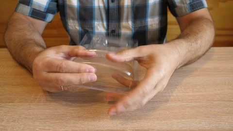 A man crumples clear plastic packaging in his hands, creating a distinctive c Stock Footage 341254642