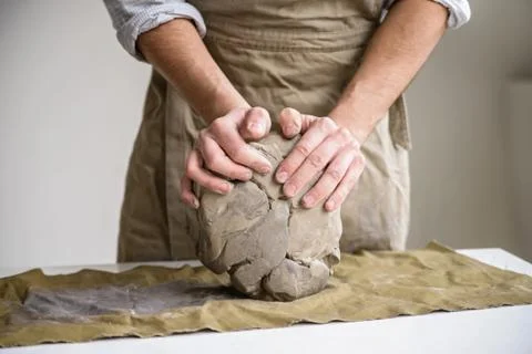 Man crumples piece of white clay for sculpting Stock Photos
