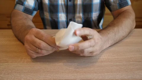 A man crumples soft plastic packaging material in his hands, creating a disti Stock Footage 341254865