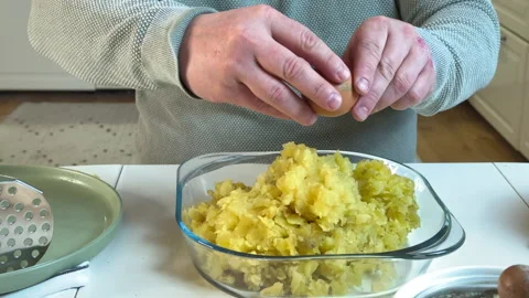 A man crushes boiled potatoes to make potato patties Stock Footage 303169166