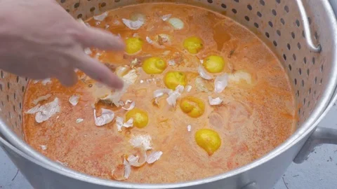 Man Crushes Garlic into a Large Pot of Spicy Cajun Broth at a Crawfish Boil Stock Footage 74980911