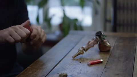 Man crushing and putting weed in smoking pipe Stock Footage 107955152