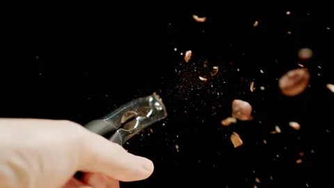 Man crushing a nut with a steel nutcracker. Slow motion. Stock Footage 144415876